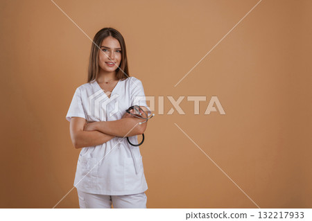 Cheerful nurse. Young pretty woman is against background in the studio 132217933