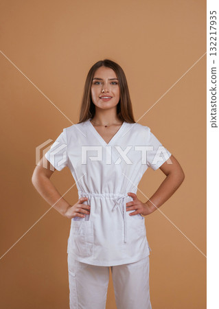 Cheerful nurse. Young pretty woman is against background in the studio 132217935