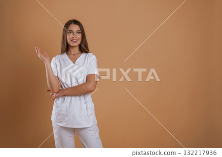 Cheerful nurse. Young pretty woman is against background in the studio 132217936