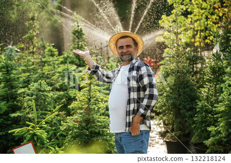 Automatic watering system behind. Senior gardener is at work at daytime 132218124