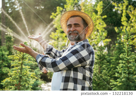 Showing the automatic watering machine. Senior gardener is at work at daytime 132218130