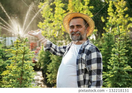 Showing the automatic watering machine. Senior gardener is at work at daytime 132218131