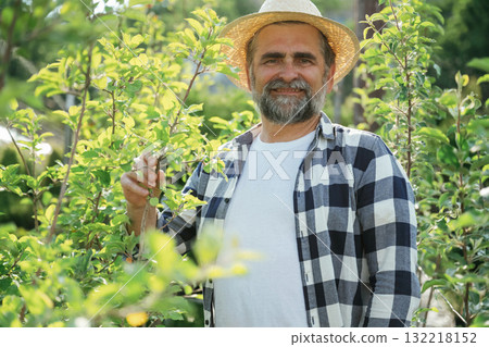 Enjoying the job. Senior gardener is at work at daytime Enjoying the job. Senior gardener is at work at daytime 132218152