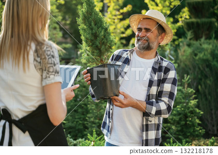 Taking a plant in a pot. Woman and man are working in the garden together with plants Taking a plant in a pot. Woman and man are working in the garden together with plants 132218178