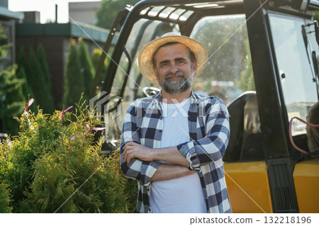 Arms crossed, standing. Senior gardener is at work at daytime Arms crossed, standing. Senior gardener is at work at daytime 132218196