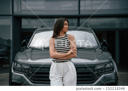 Attractive young woman is outdoors near her brand new car 132218346