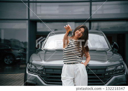 Keys for the new car. Happy owner. Attractive young woman is outdoors near her brand new car Keys for the new car. Happy owner. Attractive young woman is outdoors near her brand new car 132218347