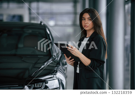 Notepad in hands. Saleswoman in car showroom, selling automobile 132218359
