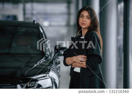 Notepad in hands. Saleswoman in car showroom, selling automobile Notepad in hands. Saleswoman in car showroom, selling automobile 132218360