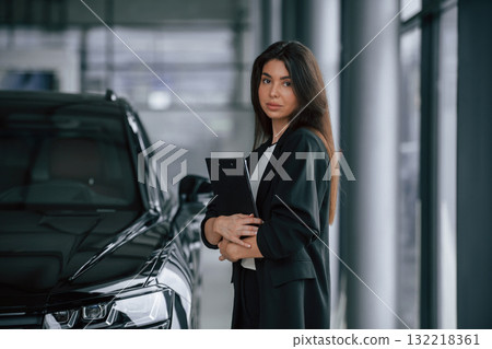 Showing the vehicle. Saleswoman in car showroom, selling automobile Showing the vehicle. Saleswoman in car showroom, selling automobile 132218361