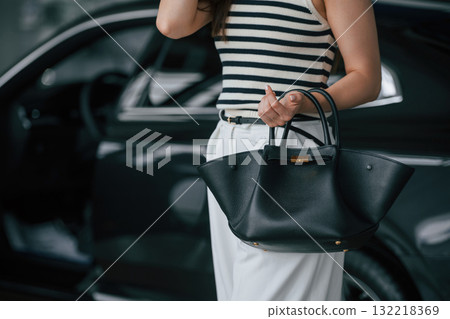 Beautiful young woman is with new automobile in car showroom Beautiful young woman is with new automobile in car showroom 132218369