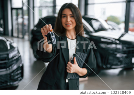 Here's the keys for the new vehicle. Saleswoman in car showroom, selling automobile Here's the keys for the new vehicle. Saleswoman in car showroom, selling automobile 132218409