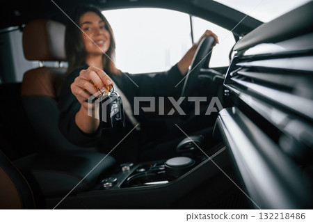 Black colored keys of new automobile. Beautiful businesswoman is in the new car Black colored keys of new automobile. Beautiful businesswoman is in the new car 132218486