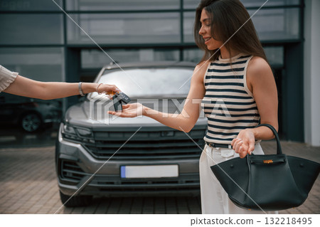 Smiling woman are taking the keys for the new automobile from another person Smiling woman are taking the keys for the new automobile from another person 132218495