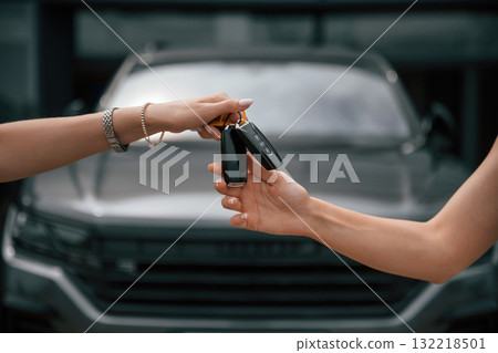 Order is finished. Woman hands are giving and taking the keys for the new automobile Order is finished. Woman hands are giving and taking the keys for the new automobile 132218501