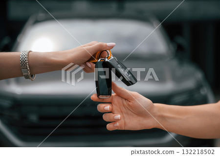 Order is finished. Woman hands are giving and taking the keys for the new automobile Order is finished. Woman hands are giving and taking the keys for the new automobile 132218502