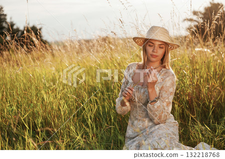 Wheat is in hands. Beautiful young woman is on the field, countryside 132218768