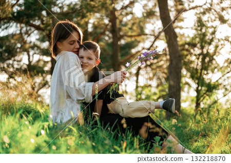 In the sunlight. Mother and son are in the forest together In the sunlight. Mother and son are in the forest together 132218870
