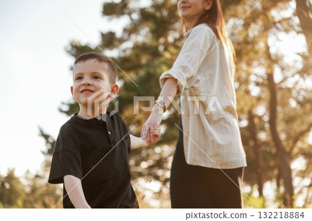 Holding each other by a hands. Mother and son are in the forest together 132218884