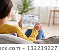 A person explores an online shop on a tablet while sitting comfortably on a couch 132219227