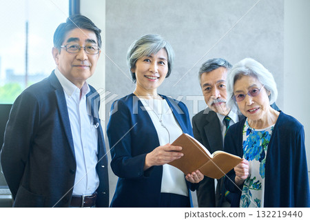 Senior business team standing in a row, smiling and holding notebooks Senior business team standing in a row, smiling and holding notebooks 132219440