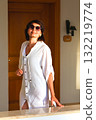 Portrait of an adult woman in white clothes at sunset near the front door of the house 132219774