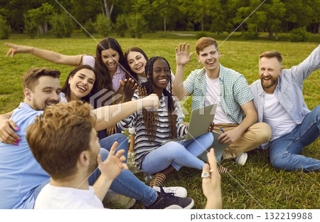 Happy college friends sitting in park, using laptop, laughing and having fun together 132219988