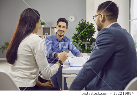 Young couple sitting back and having consultation with a man realtor or insurance agent at office. Young couple sitting back and having consultation with a man realtor or insurance agent at office. 132219994