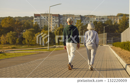 Senior couple walking together in park wearing sportswear, view from behind Senior couple walking together in park wearing sportswear, view from behind 132220009