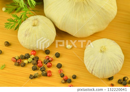 The bulbs of garlic, red chili peppers, four-color pepper, and carrot tops on a wooden cutting board. The concept of culinary arts and vegetables in the home. Macro image, close-up, top view, flat lay The bulbs of garlic, red chili peppers, four-color pepper, and carrot tops on a wooden cutting board. The concept of culinary arts and vegetables in the home. Macro image, close-up, top view, flat lay 132220041