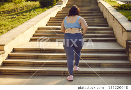 Overweight happy smiling fat woman running up the stairs in the city summer park. Overweight happy smiling fat woman running up the stairs in the city summer park. 132220048