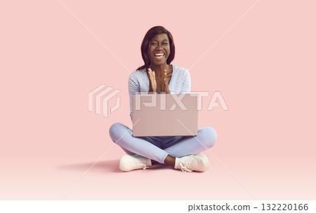 Happy excited woman sitting with a laptop clapping hands expressing happiness on pink background. 132220166