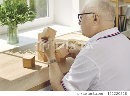Senior man with Alzheimer's disease playing with wooden cubes as a brain exercise 132220228