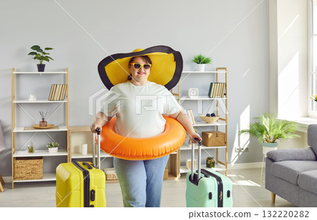 Funny happy plus size woman going on summer vacation with two suitcases and beach ring 132220282