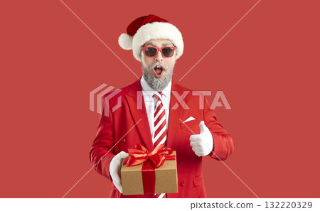 Portrait of funny surprised man who holds Christmas present in his hand and who shows thumb up. Portrait of funny surprised man who holds Christmas present in his hand and who shows thumb up. 132220329