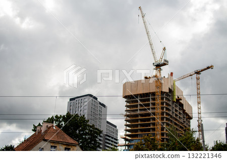 Construction site with cranes and buildings under gray skies in an urban area 132221346