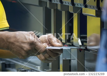 Close up the bending machine operator hold the sheet metal parts. 132223289