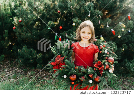 Merry Christmas. Portrait of happy funny child girls in Santa hat with Christmas wreath. Happy Holidays. Fairy Magic. Happy kid enjoying holiday. Christmas in July Merry Christmas. Portrait of happy funny child girls in Santa hat with Christmas wreath. Happy Holidays. Fairy Magic. Happy kid enjoying holiday. Christmas in July 132223717
