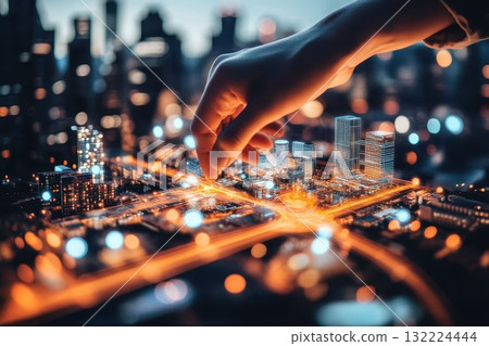Hand Touching Miniature Model of Cityscape at Night with Blurred Skyline Background 132224444