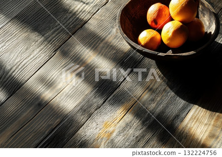 Fresh Oranges in Wooden Bowl on Rustic Table Highlighting Natural Light and Shadows Fresh Oranges in Wooden Bowl on Rustic Table Highlighting Natural Light and Shadows 132224756