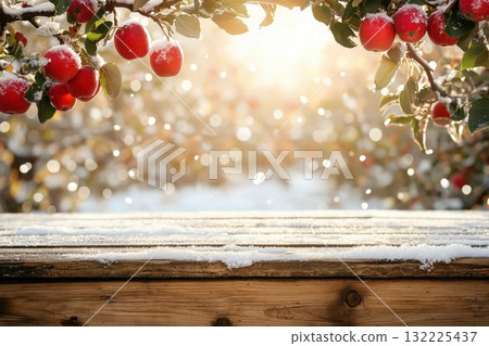 Beautiful winter landscape with fresh red apples hanging on snowy branches and a wooden table showcasing the tranquil ambiance of a snowy orchard at sunset Beautiful winter landscape with fresh red apples hanging on snowy branches and a wooden table showcasing the tranquil ambiance of a snowy orchard at sunset 132225437