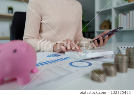 Financial analysis. Woman calculating expenses with smartphone and calculator at desk. Financial analysis. Woman calculating expenses with smartphone and calculator at desk. 132225493