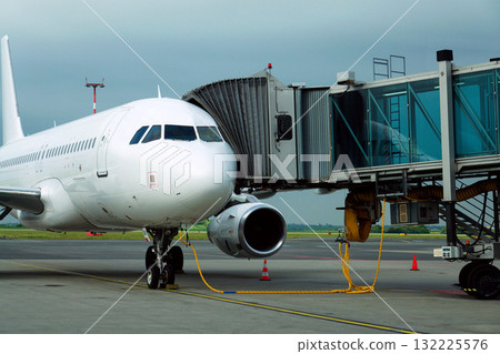 Charter airline airplane preparing for flight on airport runway with connected jet boarding bridge 132225576