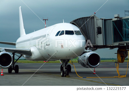 Charter airline airplane preparing for flight on airport runway with connected jet boarding bridge 132225577