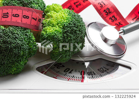 Broccoli with measuring tape on weight scale. Dieting Broccoli with measuring tape on weight scale. Dieting 132225924