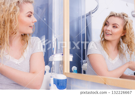 Woman looking at herself in bathroom mirror 132226667