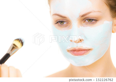 Girl apply green mud mask to face Girl apply green mud mask to face 132226762