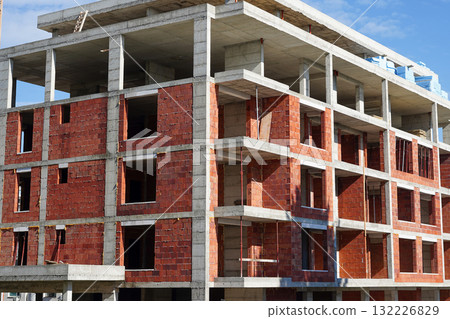 An unfinished brick and concrete building under construction against a blue sky An unfinished brick and concrete building under construction against a blue sky 132226829