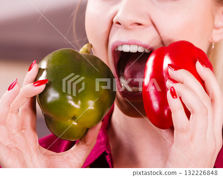 Funny woman taking bite of bell pepper 132226848