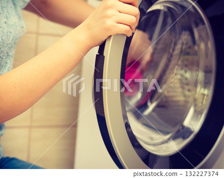 Person putting clothes into washing machine Person putting clothes into washing machine 132227374